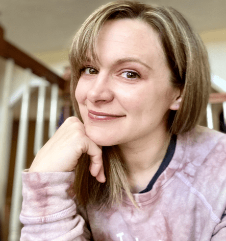 Smiling woman in casual sweatshirt, hand on chin
